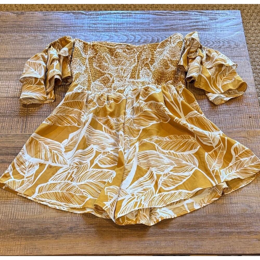 Stylish off-shoulder romper with a golden leaf print. Features puff sleeves.